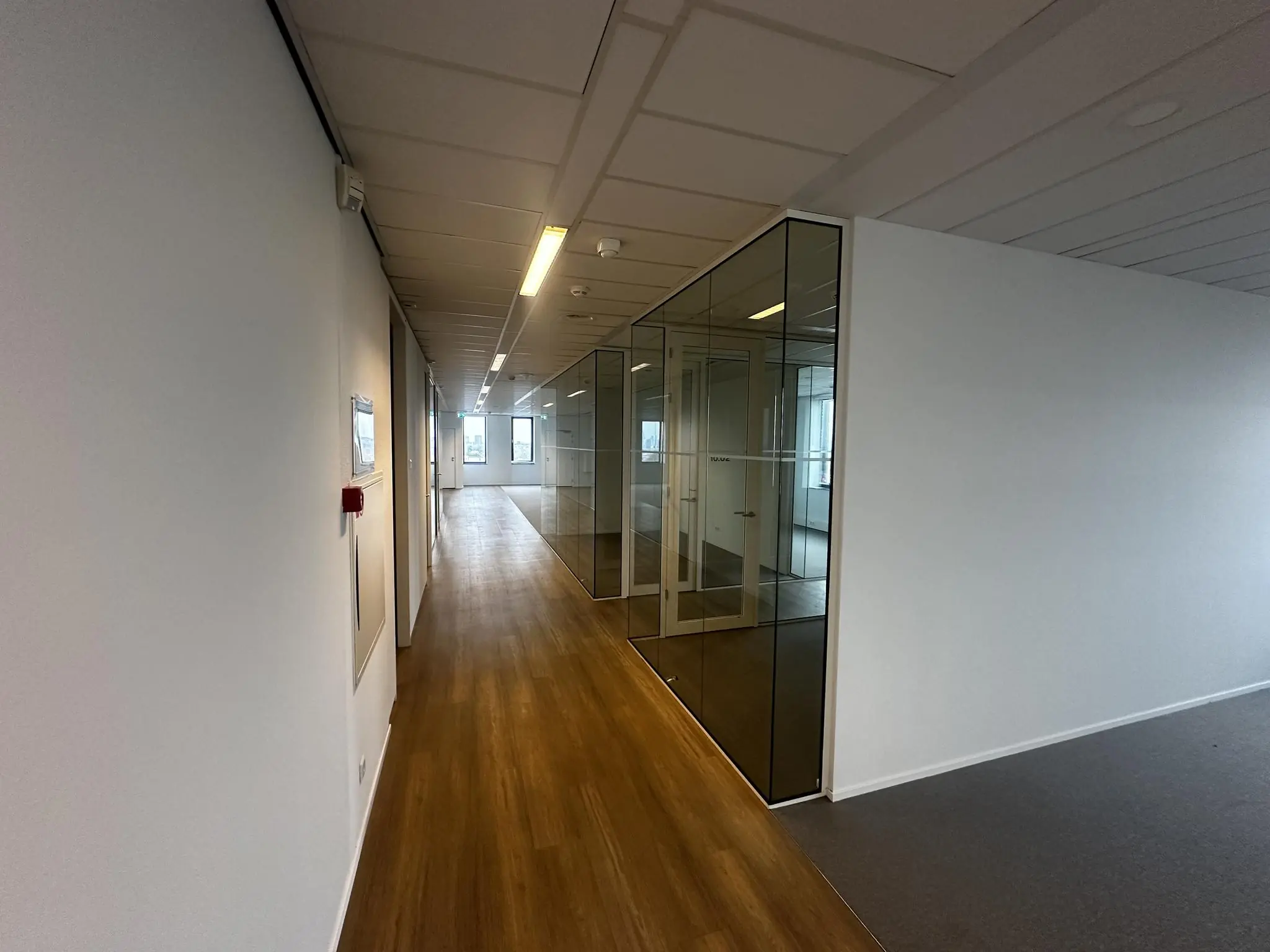 Lichte kantoorgang met glazen vergaderruimtes aan de Laan van Zuid Hoorn.